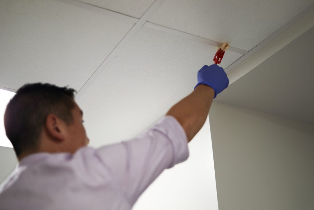 A Man using a sampling sponge to environmentally sample the ceiling